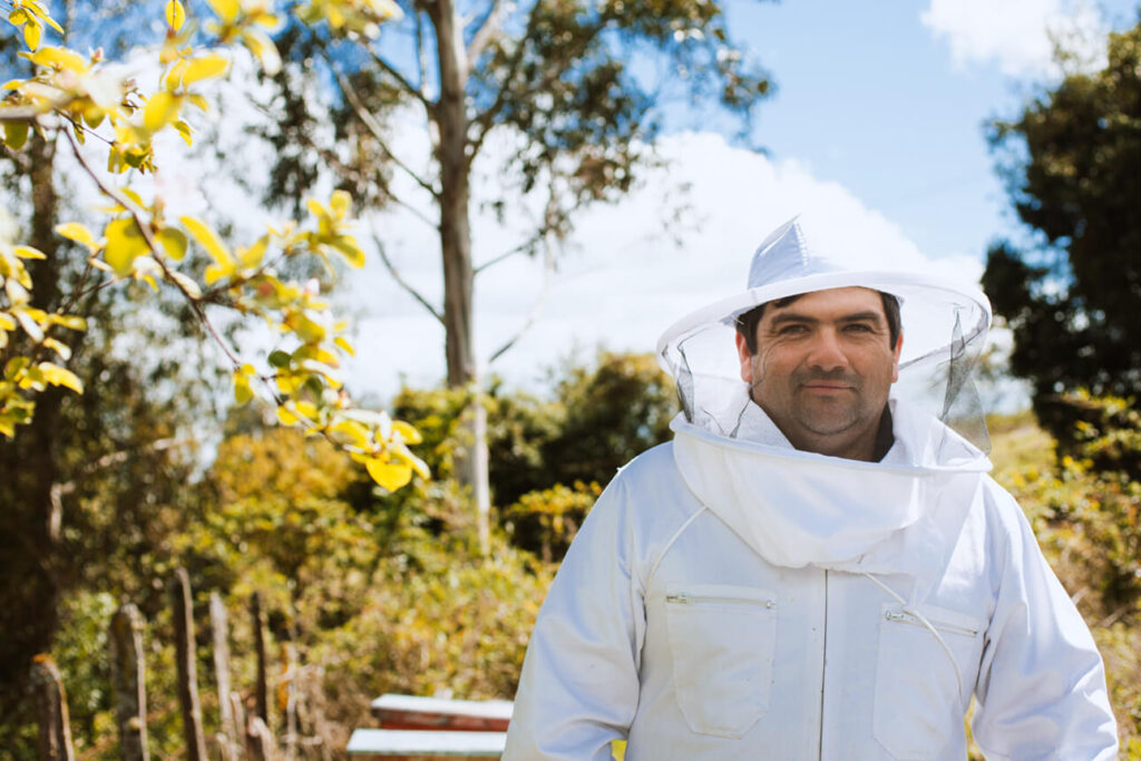 Imker David in een wit imkerpak, midden in de natuur